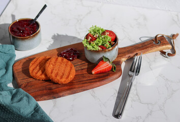 A portion of fresh made fried camembert cheese with cranberry sauce and a side salad