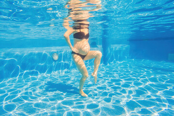 Embracing aquatic fitness, a pregnant woman demonstrates strength and serenity in underwater...