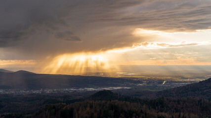 The rays of the setting sun transform an approaching rain shower into a light show