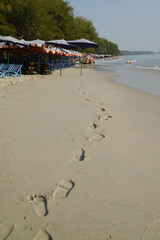 Footprints on Cha-am beach There are beach deck chairs and large umbrellas available to tourists. Located at Phetchaburi Province in Thailand.