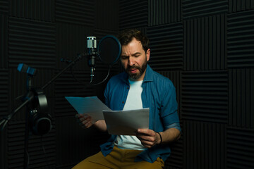 Man working as a voice actor reading the script and getting ready to start recording - 778537385