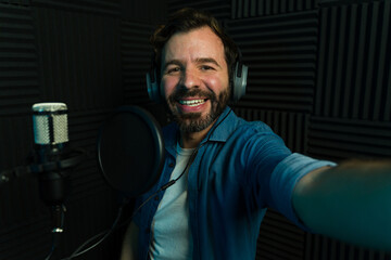 Smiling male podcaster taking selfie in studio - 778537563