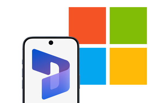 Dynamics 365 Logo is displayed on a modern smartphone, Microsoft logo behind it, enterprise resource planning (ERP) and customer relations management