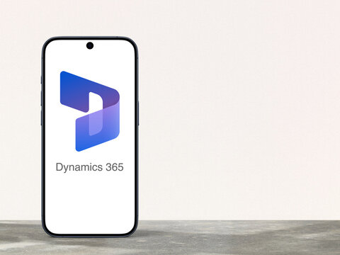 Microsoft Dynamics 365 Logo is displayed on a modern smartphone standing on a desk, enterprise resource planning (ERP) and customer relations management