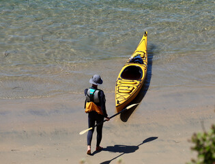 man launching his kayak onto the bay