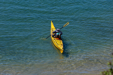 man launching his kayak onto the bay
