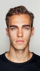 Obraz premium Modern Masculinity: Casual Male Portrait. Studio portrait of a young man with styled hair and a black shirt, exuding casual confidence.
