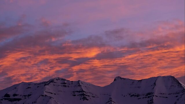Sunrise timelapse over snow capped Timpanogos Mountain as the clouds light up with vibrant colors in Utah.