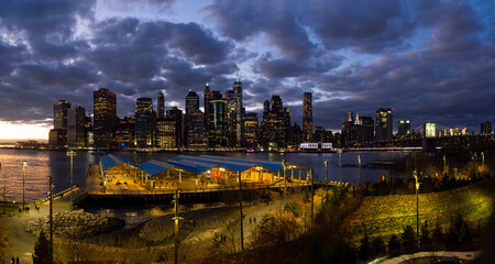 Panoramic of Manhattan skyline at night from Brooklyn Bridge Park. New York City skyscrapers,...