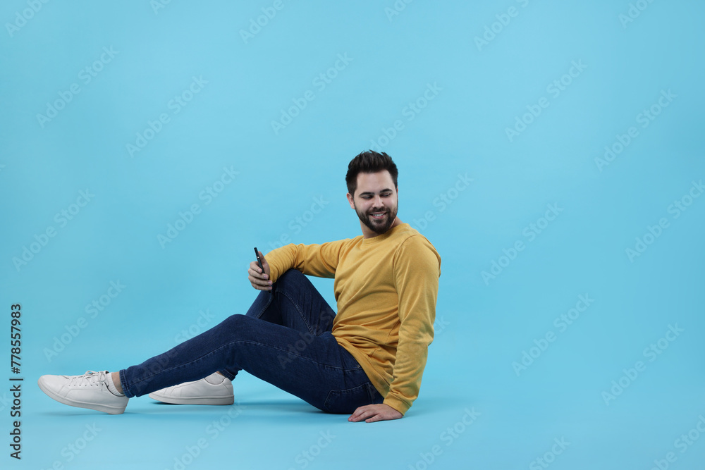 Canvas Prints handsome young man using smartphone on light blue background, space for text