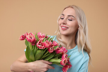 Happy young woman with beautiful bouquet on beige background