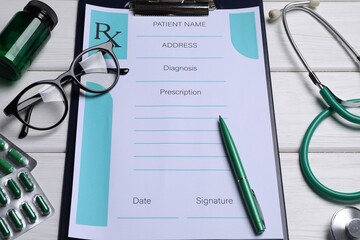 Clipboard with medical prescription form, stethoscope, pills and glasses on white wooden table