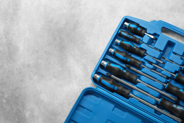 Set of screwdrivers in open toolbox on light grey textured table, top view. Space for text