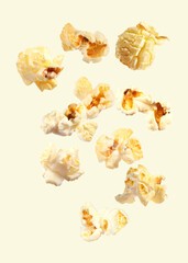 Tasty fresh popcorn flying on beige background