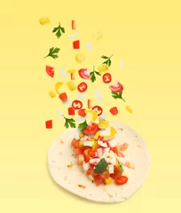 Foto op Canvas Delicious taco with flying ingredients on yellow background © New Africa