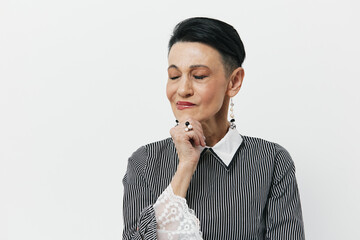 Thoughtful young woman with short hair in a black and white striped shirt looking contemplatively with hand on chin