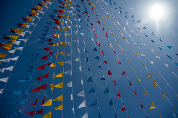 Colorful triangle flag waving unde blue sky. - 778566145