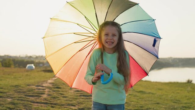 Little girl parasol dances in golden light