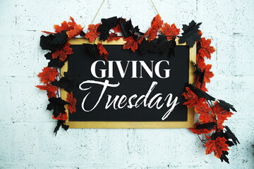Giving Tuesday text message on chalkboard with maple leaf decoration