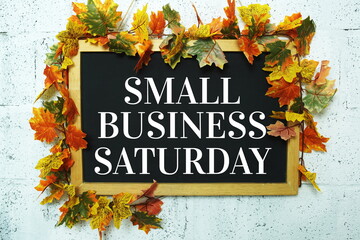 Small Business Saturday typography text on wooden blackboard hanging with maple leaf decoration