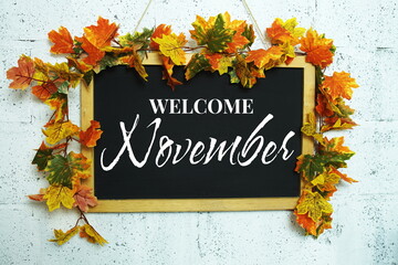 Welcome November text message on chalkboard with maple leaf decoration