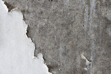 Torn old faded paper wallpaper on a concrete wall. Ragged scraps of white paper on a gray...