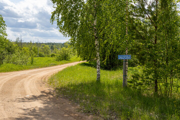 Country road in the countryside. On the side of the road there is a sign with the name of the village in Russian “Zaborovye”. Novgorod region, Russia. Traveling through villages of Russia. Summer. - 778598171
