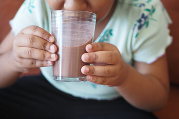  little girl drinking tasty chocolate milk at home.