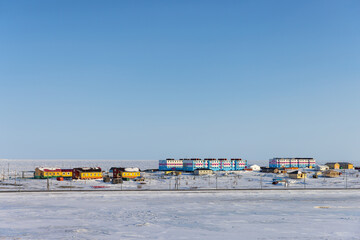 Chukotka village Tavaivaam, Chukotka Autonomous Okrug, Russia. View of a small Arctic village on the shore of a frozen sea. Colorful buildings in a well-maintained northern settlement - 778599112