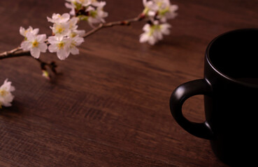 Spring cafe or spring dining table. Cherry blossom branches and a cup with a drink on the table. 春のカフェまたは春の食卓。テーブルの上の桜の枝と飲み物の入ったコップ。