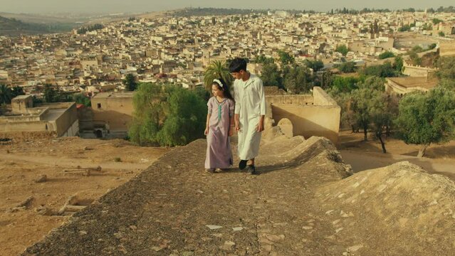 Kids walking and Overlooking Old City of Fes in Morocco in traditional clothes