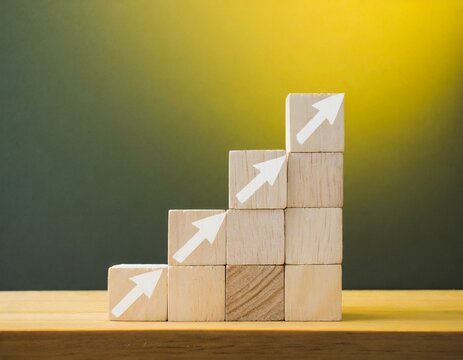 Stacking wooden blocks and up arrow on a wooden table, continuous improvement concept