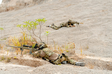 Two military or soldiers lie down on the ground with hold gun point to the opposite side on...