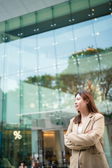 Fototapeta premium Asian white collar business woman standing outside office city building