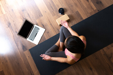 Top view of young woman wearing sports clothes doing online meditation and yoga class at home using laptop.. Copy space. - obrazy, fototapety, plakaty