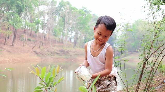 Asian boy watering plants with plastic bottle.