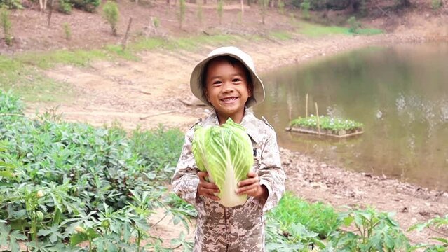 A boy is holding vegetables and shaking them with a joyful smile.