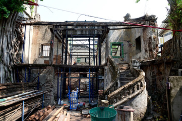BANGKOK, THAILAND - April 07,2024: Closeup of Old cement house with cracked bricks Waiting for restoration, it is covered with the roots of large trees background at Thailand.