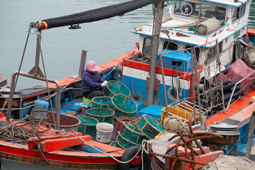 Fototapeta na wymiar A woman repairing fishing nets on the boat