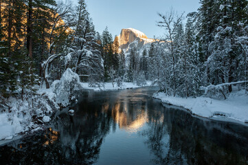Half dome reflected in the merced river, while it is illuminated by the setting sun. Yosemite national park. - Powered by Adobe
