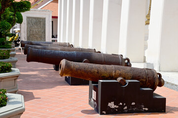 BANGKOK, THAILAND - April 11, 2024: The ancient black rusted cannon is located on the white wall In...