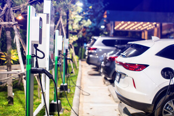 EV charging station with blurry an electric car. Power supply for electric car charging. Socket for electrical car battery charger. EV car charging station in parking. Nature energy, Green eco concept