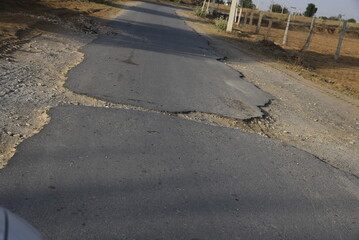 Bad road, cracked asphalt with potholes and big holes. Potholes on the road with stones on the asphalt. The asphalt surface is destroyed on the road. Bad condition of the road - 778663707