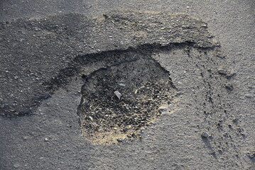 Bad road, cracked asphalt with potholes and big holes. Potholes on the road with stones on the asphalt. The asphalt surface is destroyed on the road. Bad condition of the road - 778663753