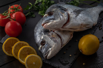 Sea bream or dorado sea fish herbs on dark slate background Top view 