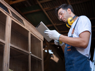 Professional Carpenter happy working to making woodcraft furniture in wood workshop look...