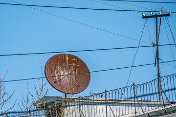 An old satellite TV antenna on the roof of a house on a spring day