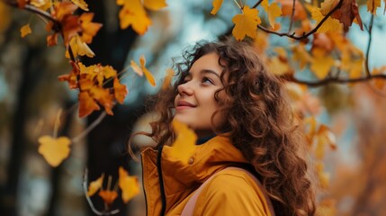 Young woman in jacket look at Automn leaves in park female Caucasian smiling curly long hair