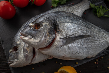 Sea bream or dorado sea fish herbs on dark slate background Top view 