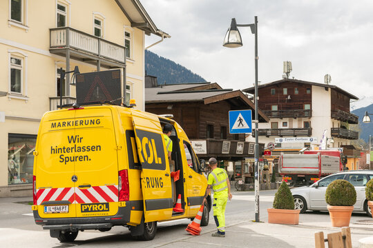 Yellow van with markings "road marking" standing in the street. Workers in yellow clothing putting road cones in a van after putting new road markts on the street. 04 april 2024, Oetz, austria.